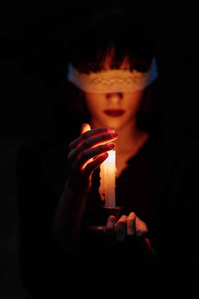 blindfolded woman holding a candle