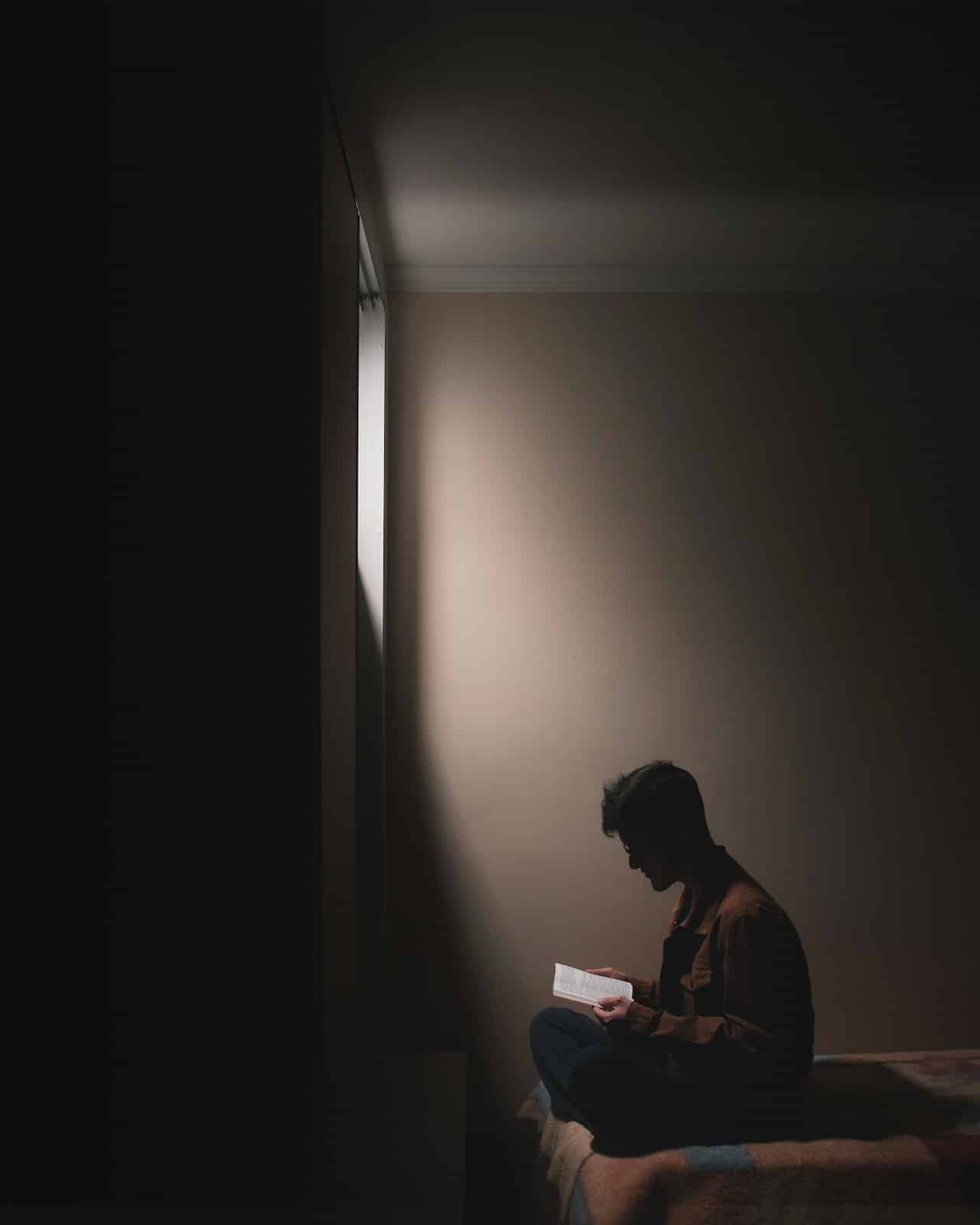 Man sitting in the dark reading a book