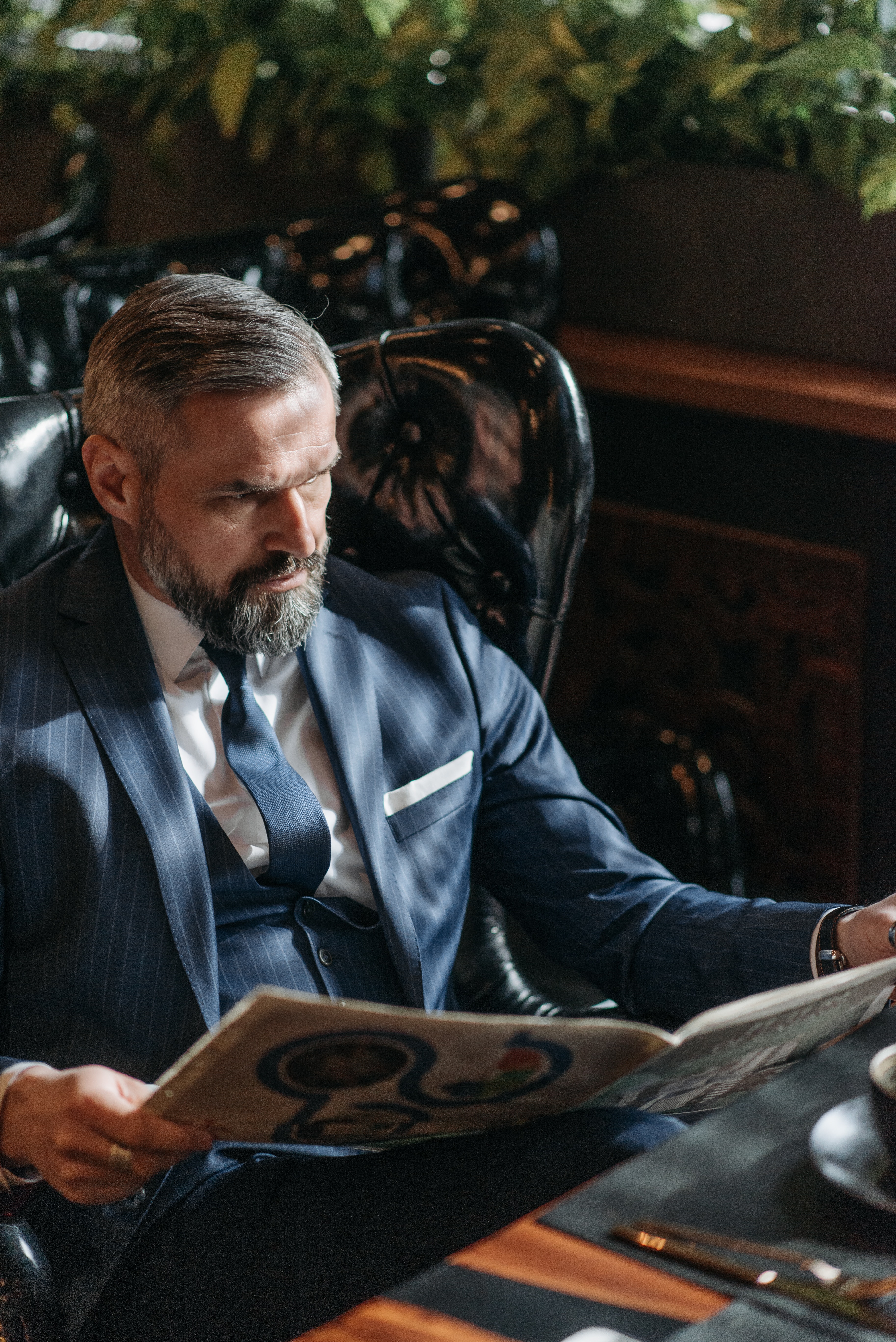 A successful man in a blue suit reading a magazine